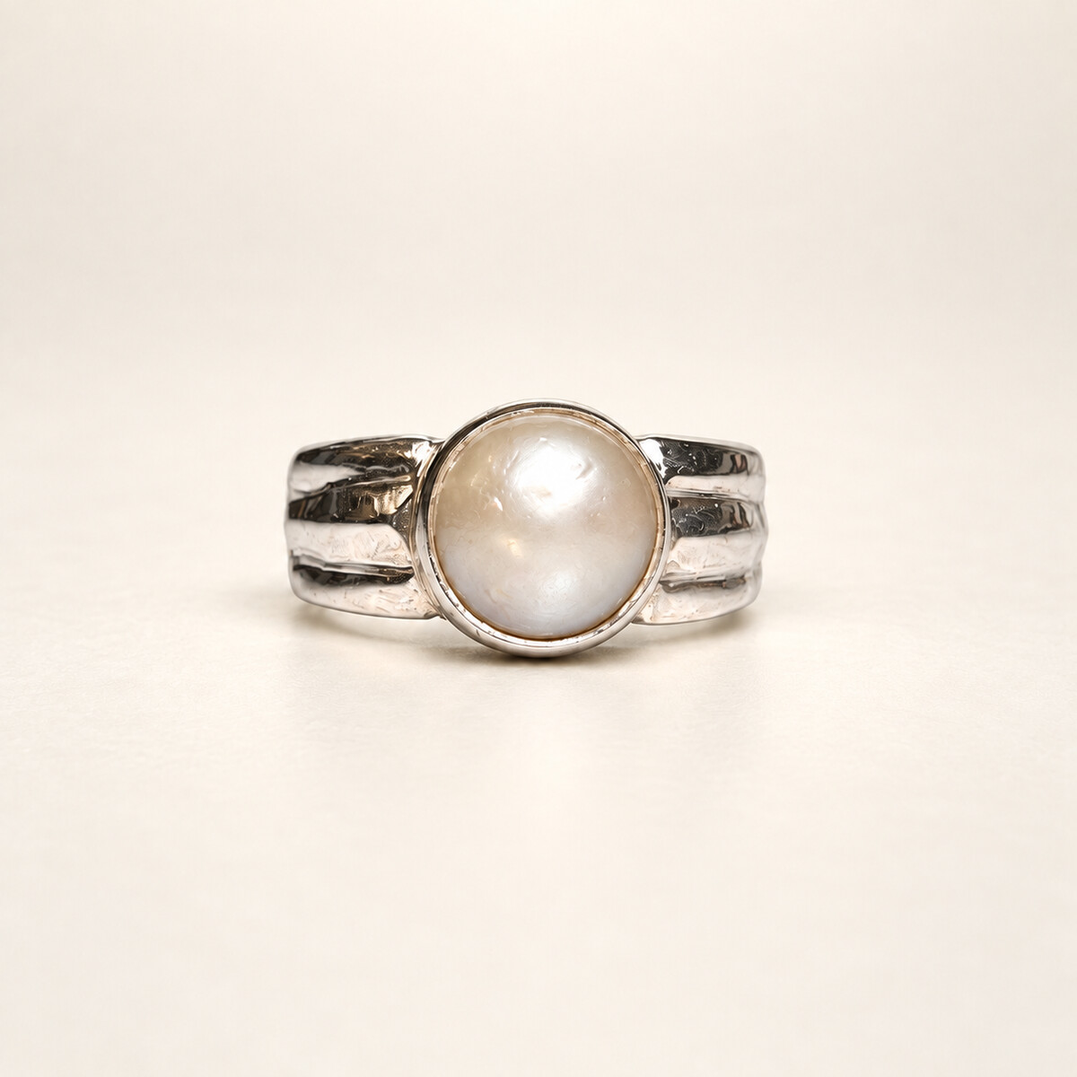 Cream-white Moti pearl set in a silver ring on a warm ivory studio background