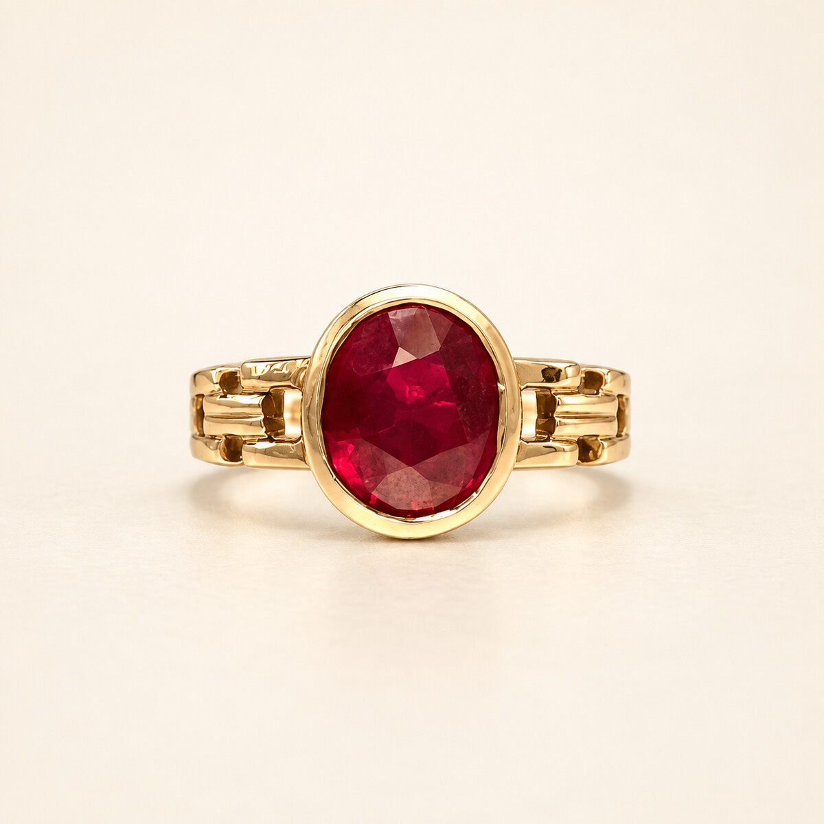 Deep red faceted Ruby set in a polished gold ring on a warm ivory studio background